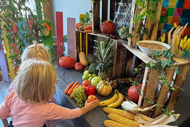 Zwei Kinder gestalten den mit Obst und Gemüse dekoreierten Erntedankaltar.