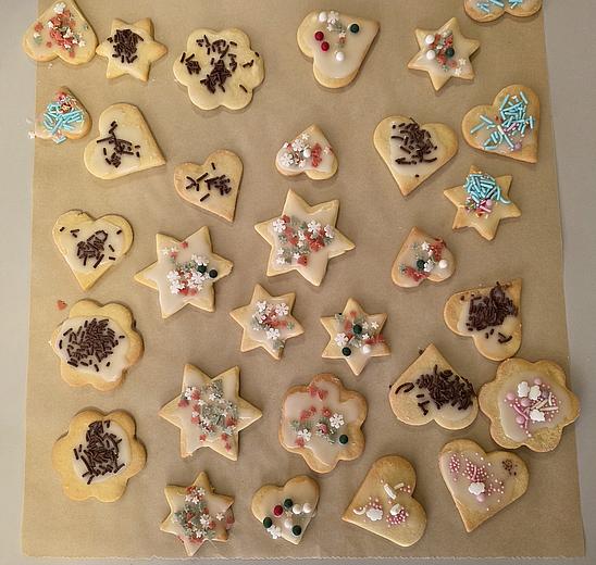 Das Bild zeigt Bachpapier mit vielen verschiedenen Plätzchen in Form von Herzen und Sternen. Alle sind bunt verziert mit bunten Zuckerperlen und Schokosträußeln.