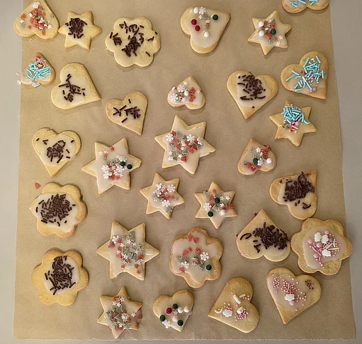 Das Bild zeigt Bachpapier mit vielen verschiedenen Plätzchen in Form von Herzen und Sternen. Alle sind bunt verziert mit bunten Zuckerperlen und Schokosträußeln.