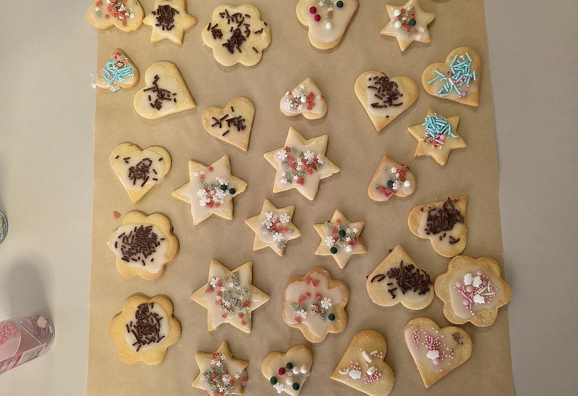 Das Bild zeigt Bachpapier mit vielen verschiedenen Plätzchen in Form von Herzen und Sternen. Alle sind bunt verziert mit bunten Zuckerperlen und Schokosträußeln.